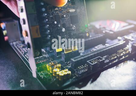 Proffesional soundcard being installed to motherboard by PC technician. PCI sound card upgrade or repair concept. Stock Photo