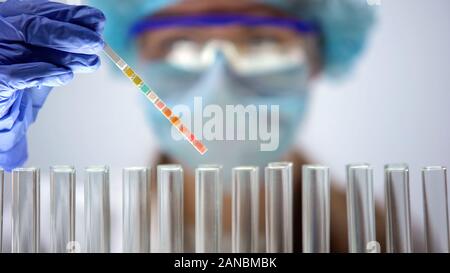 Scientist holding litmus paper analyzing reaction, chemical experiment, test Stock Photo