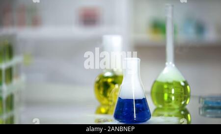 Sample of blue substance in flask standing on table of laboratory, washing agent Stock Photo