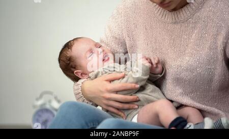 Mother trying to calm crying baby, infant colic problem causes parent depression Stock Photo