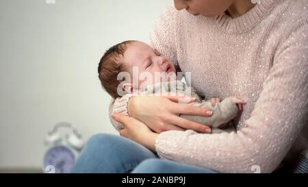 Mom calming crying infant, problems with falling asleep, sleepless night Stock Photo