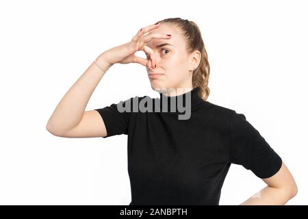 Studio shot of a young woman holds her nose and pulls a grimasse Stock Photo