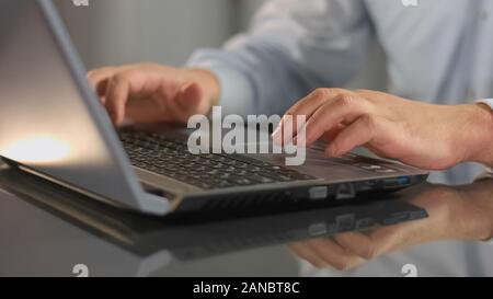 Male hands typing on laptop, company employee working office, information search Stock Photo