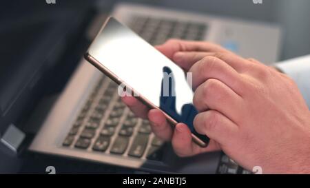Male hands typing message on smartphone closeup, scrolling photos, business app Stock Photo