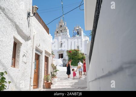 Filoti Naxos - August 13 2019: Three woman with small child walk up steps on path between white village buildings towards church in Greek Island villa Stock Photo
