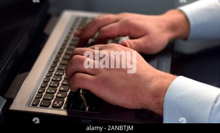Male office employee typing on laptop, software engineer working on project Stock Photo