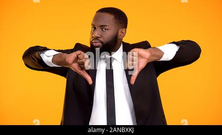 Deeply dissatisfied black man showing double thumbs-down, poor quality service Stock Photo
