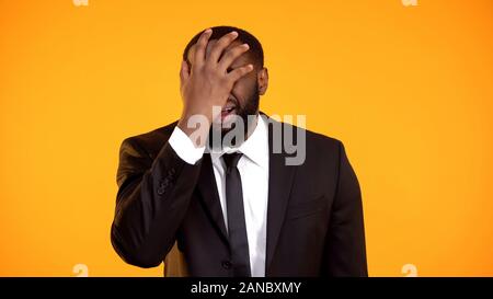 Deeply disappointed and shocked african-american male in suit making facepalm Stock Photo