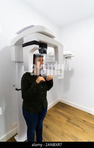 Young woman patient standing in x-ray machine. Panoramic radiography. Medical concept. Stock Photo