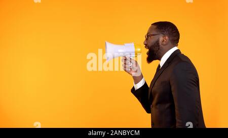 Black team leader making announcement in megaphone, stressful job, deadline Stock Photo