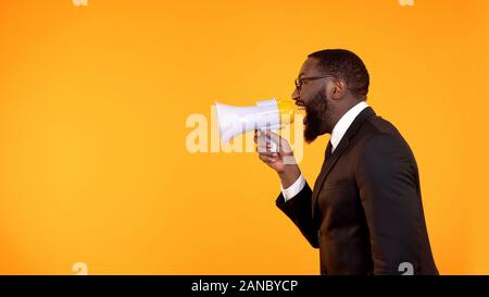 Black boss shouting in megaphone, stressful job, project deadline, announcement Stock Photo