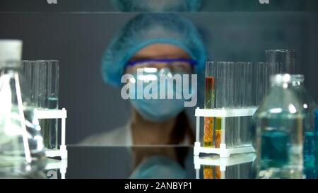 Scientist looking at tubes with meat sample in laboratory, food quality control Stock Photo