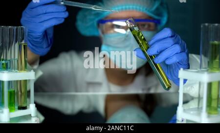Ecologist adding liquid to plant sample in tube, observing reaction, experiment Stock Photo