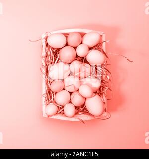 Multicolor eggs in a white tray. Creative Easter concept. Modern solid yellow background. Square. Living coral theme - color of the year 2019 Stock Photo
