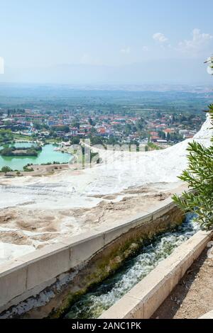 View of the unique Pamukkale natural complex with white cliffs, an emerald lake, a picturesque village and a beautiful valley. The flow of thermal wat Stock Photo