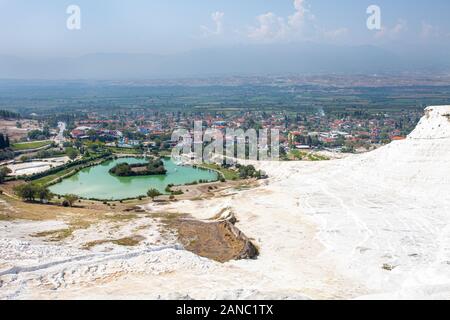View of the unique Pamukkale natural complex with white cliffs, an emerald lake, a picturesque village and a beautiful valley. Stock Photo