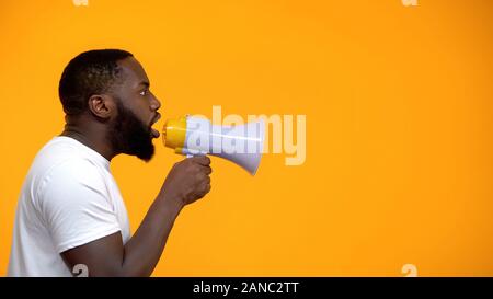 African-American man using megaphone for protest, calling to action, side view Stock Photo