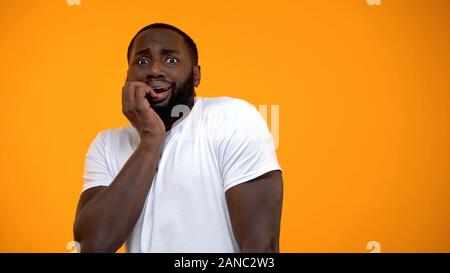 Ridiculous African-American man feeling fear isolated on yellow background Stock Photo