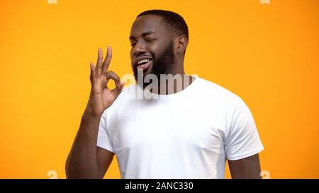 Flirty Afro-American man showing OK sign and winking, customer review, service Stock Photo