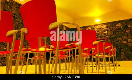 Low perspective on rows of plastic red chairs. Stock Photo