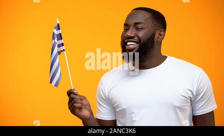Smiling African-American man holding Greece flag, international friendship Stock Photo