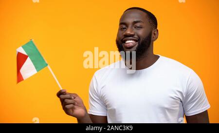 Smiling Afro-American man holding Italian flag, international friendship concept Stock Photo