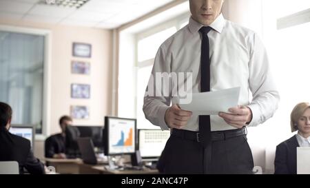 Serious businessman reading contract, office employees working on background Stock Photo