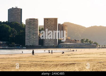 View of Praia do Itarare beach and the Ilha Porchat island on the background. People on a brazilian beach on a sunny day. Photo taken at Sao Vicente S Stock Photo