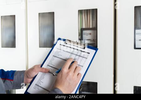 Close-up Of A Technician Hand Writing Reading Of Meter On Clipboard Stock Photo