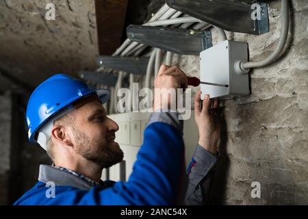 Close-up Of Young Male Technician Opening Cable Box With Screwdriver Stock Photo