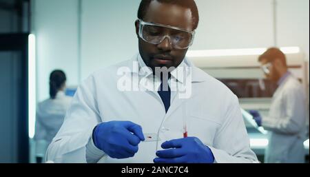 A Scientist Is Using A Microscope To Examine A Blood Sample. Test Tubes 