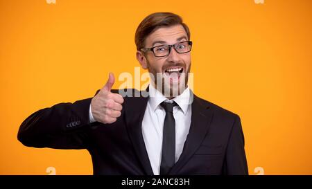 Smiling businessman showing thumbs up at camera, making good proposition Stock Photo
