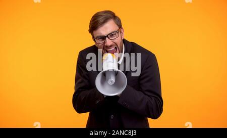 Angry boss shouting at employees using megaphone, harassment at work, stress Stock Photo