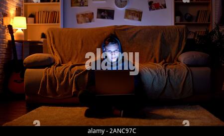 Teenager surfing internet on laptop, visiting gambling sites, young hacker Stock Photo