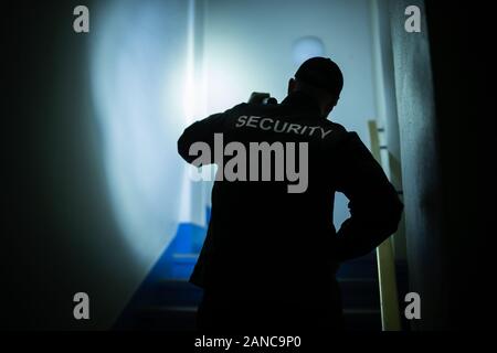Security Guard Searching On Stairway With Flashlight Stock Photo