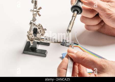 a technician solders cable to a plug with a soldering iron Stock Photo