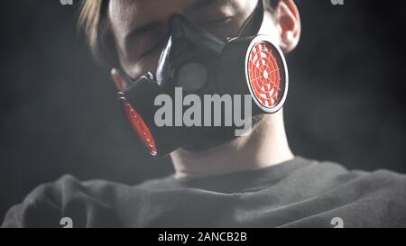 Male in respirator sleeping in smoke, protection from suffocation when fire Stock Photo