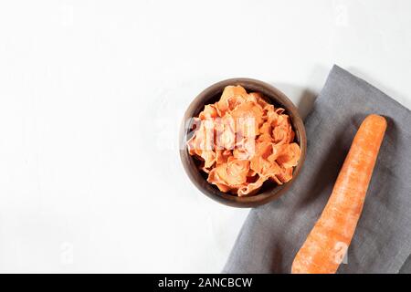Dried carrot chips in a wooden bowl on a black stone background. Organic natural food. Top view, flat lay. Copy space. Stock Photo
