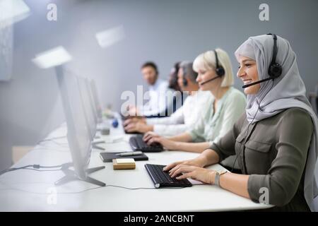 Positive Female Customer Services Agent With Headset Working In A Call Center Stock Photo