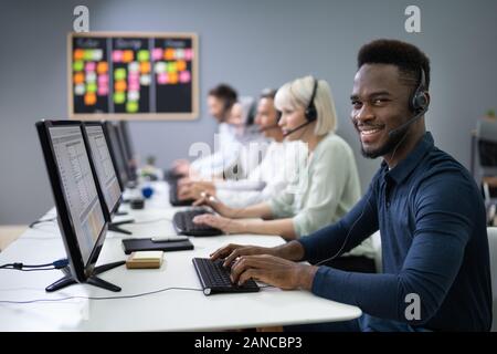 Positive Male Customer Services Agent With Headset Working In A Call Center Stock Photo