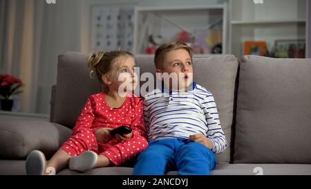 Small children watching television at night caught by parents, entertainment Stock Photo