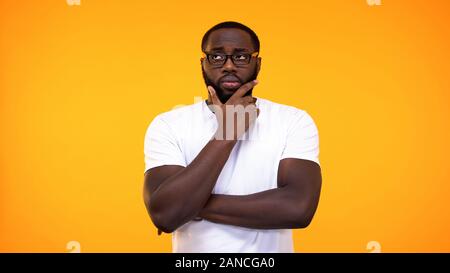 Smart young black student in glasses thinking about answer, yellow background Stock Photo
