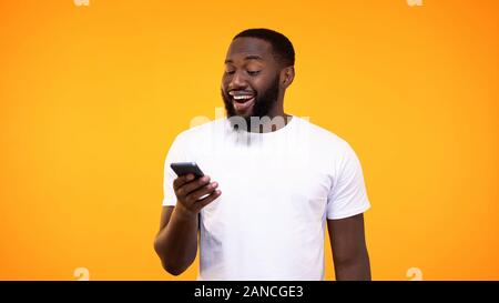 Amazed african man browsing smartphone internet, online application, cash back Stock Photo