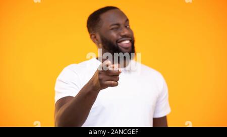 Young black man pointing finger on camera and smiling against yellow background Stock Photo