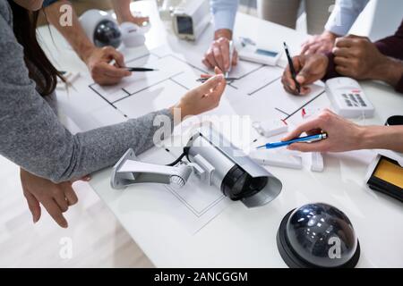 Group Of Security Engineers Working On Blueprint With Security Equipment On Table Stock Photo
