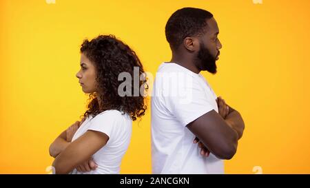 Offended multiracial couple ignoring each other standing back, relations crisis Stock Photo