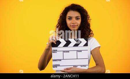Attractive black woman holding clapper board, film studio, actor audition, clip Stock Photo