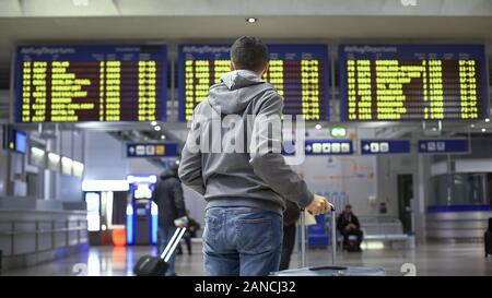 Man traveler looking at time table in train station, preparing for departure Stock Photo