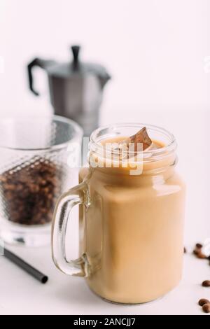 Iced coffee in jar, mug glass cup on the white table. Stock Photo