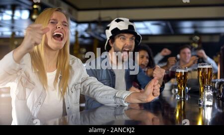 Cheerful football supporters celebrating scoring goal in pub, enjoying game Stock Photo